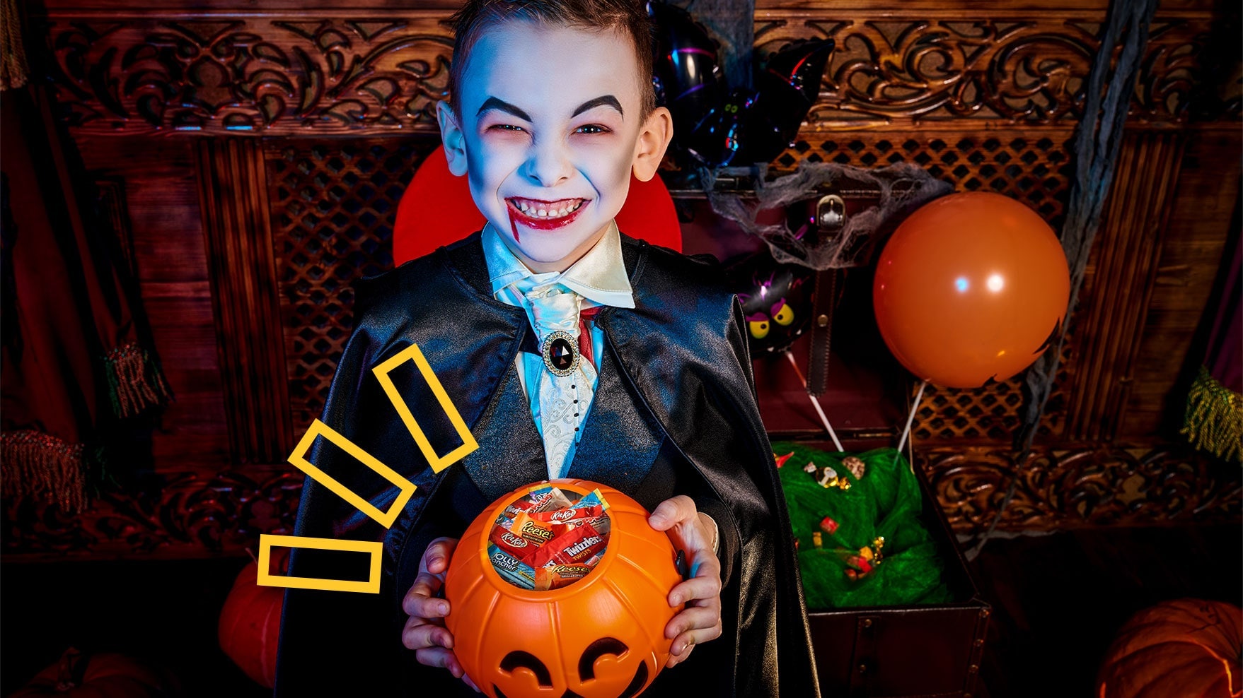Kid dressed up as a vampire holding a bucket of candy