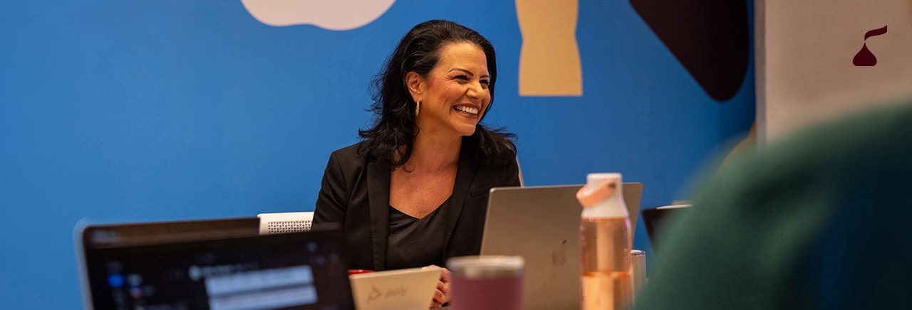 Person sitting at a table in a Hershey's conference room with a laptop