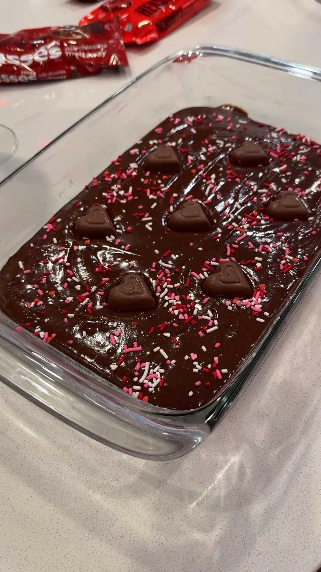 batch of freshly made brownies topped with hersheys hearts chocolate candy